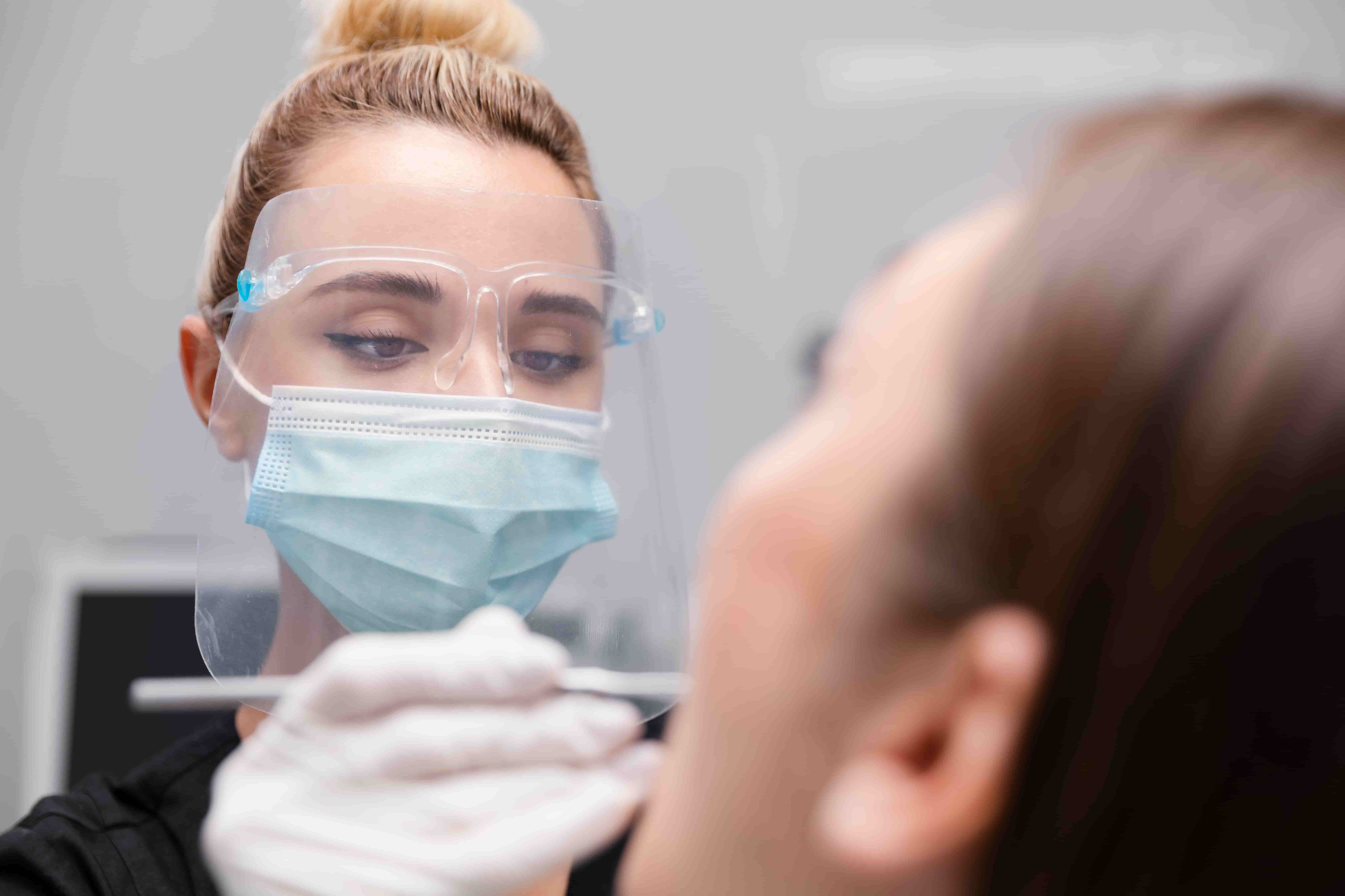 Стоматолог осматривает ротовую полость пациента